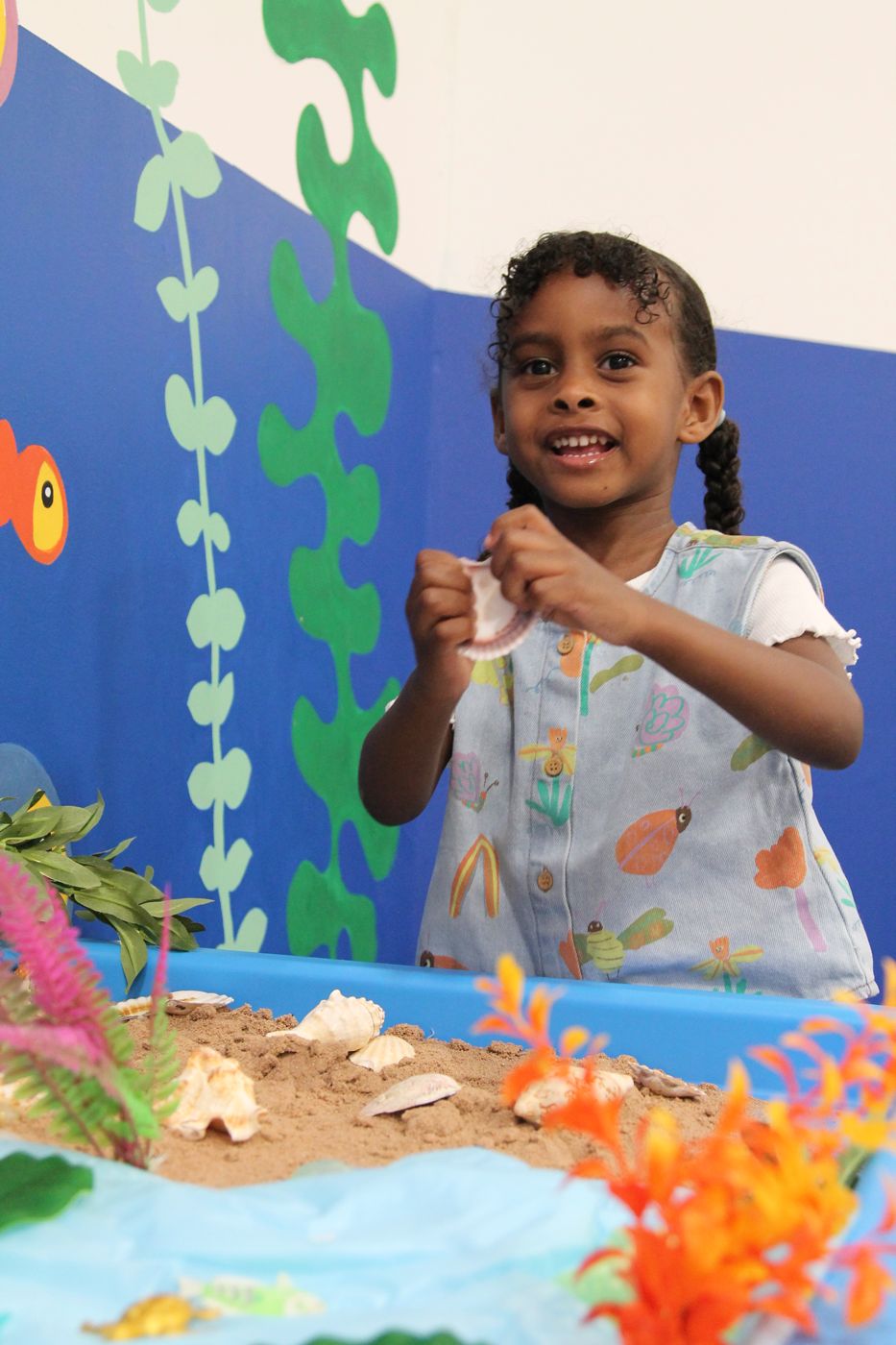 Child playing at the sand tray by the ocean mural