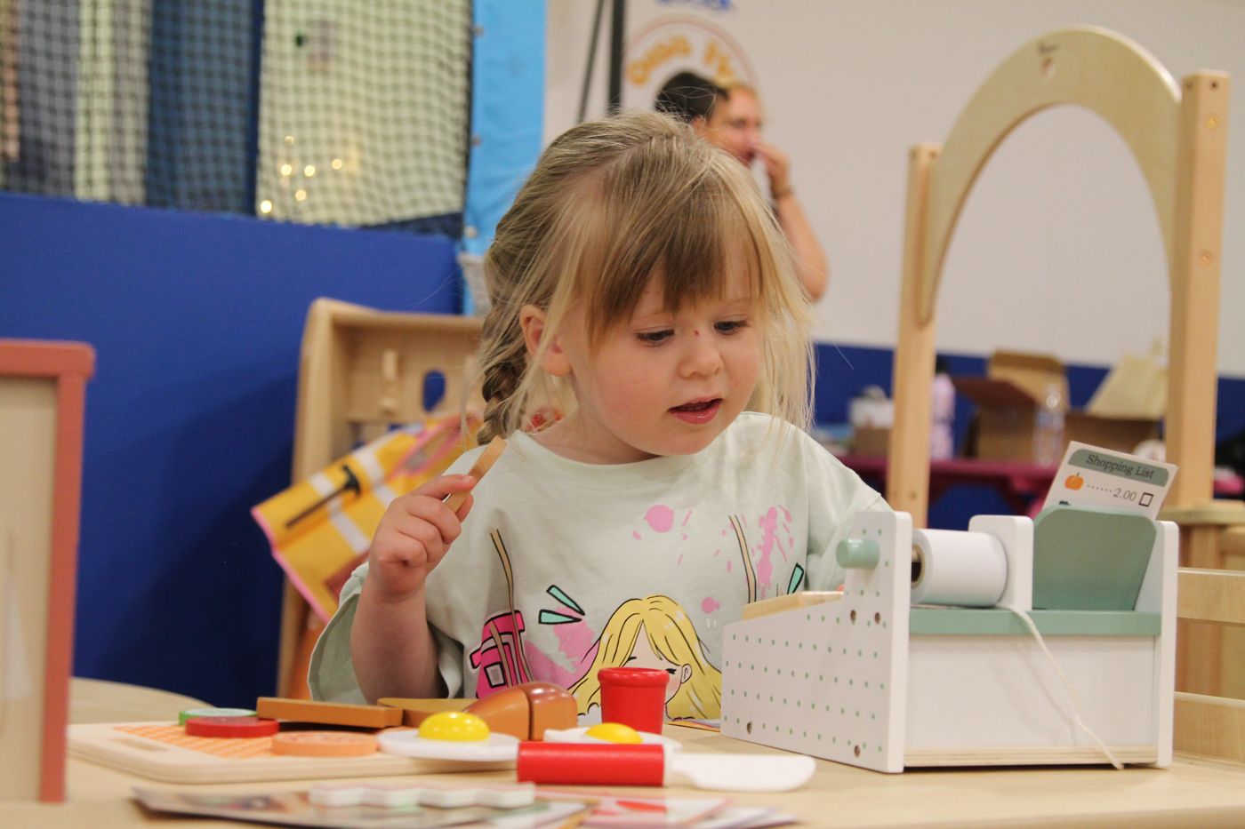 Child playing shopkeeper with a wooden till