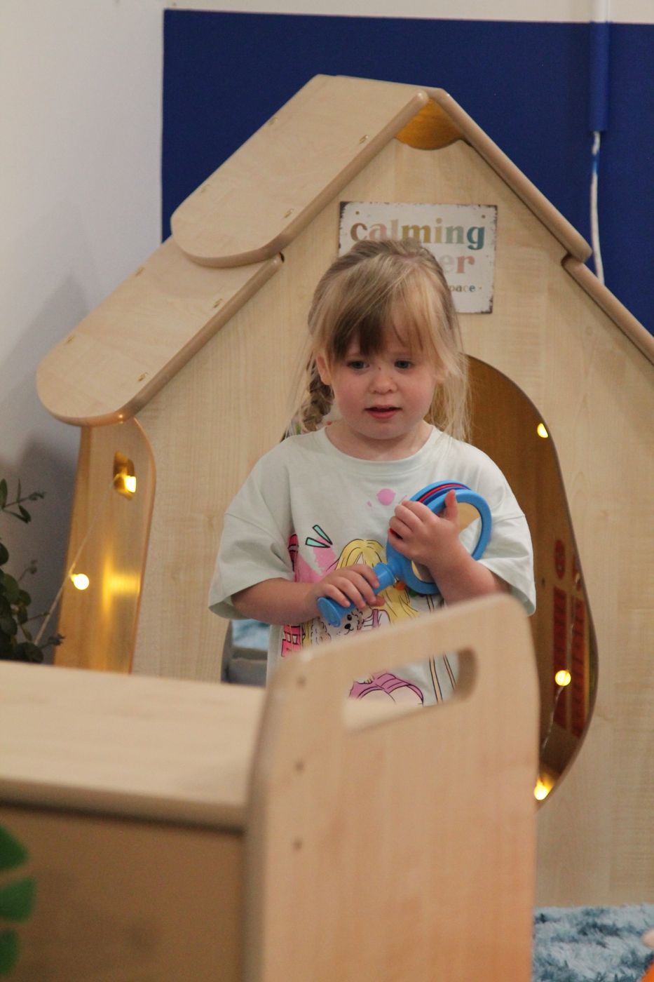 Child peeking out of a wooden den with fairy lights
